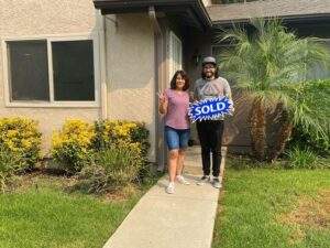 Two people standing in front of a sold house in Simi Valley.