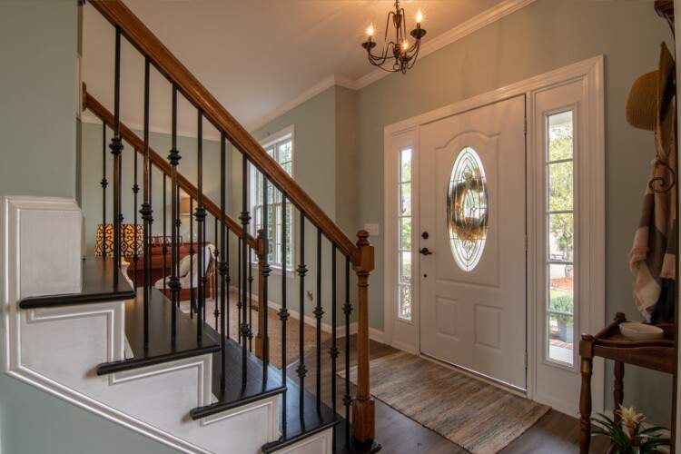 Elegant entryway with a wooden staircase and white front door.